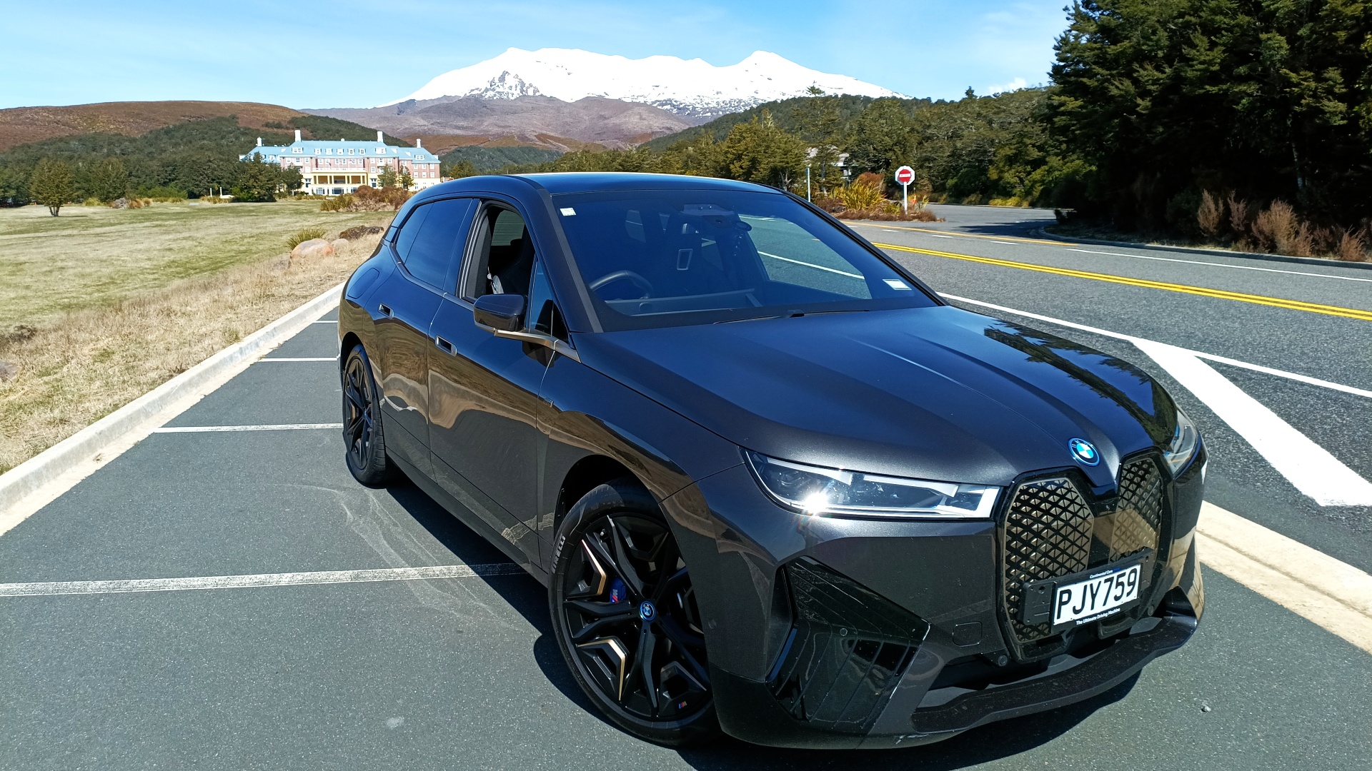 A BMW iX M60 parked in front of Mount Ruapehu after a successful long-distance road trip