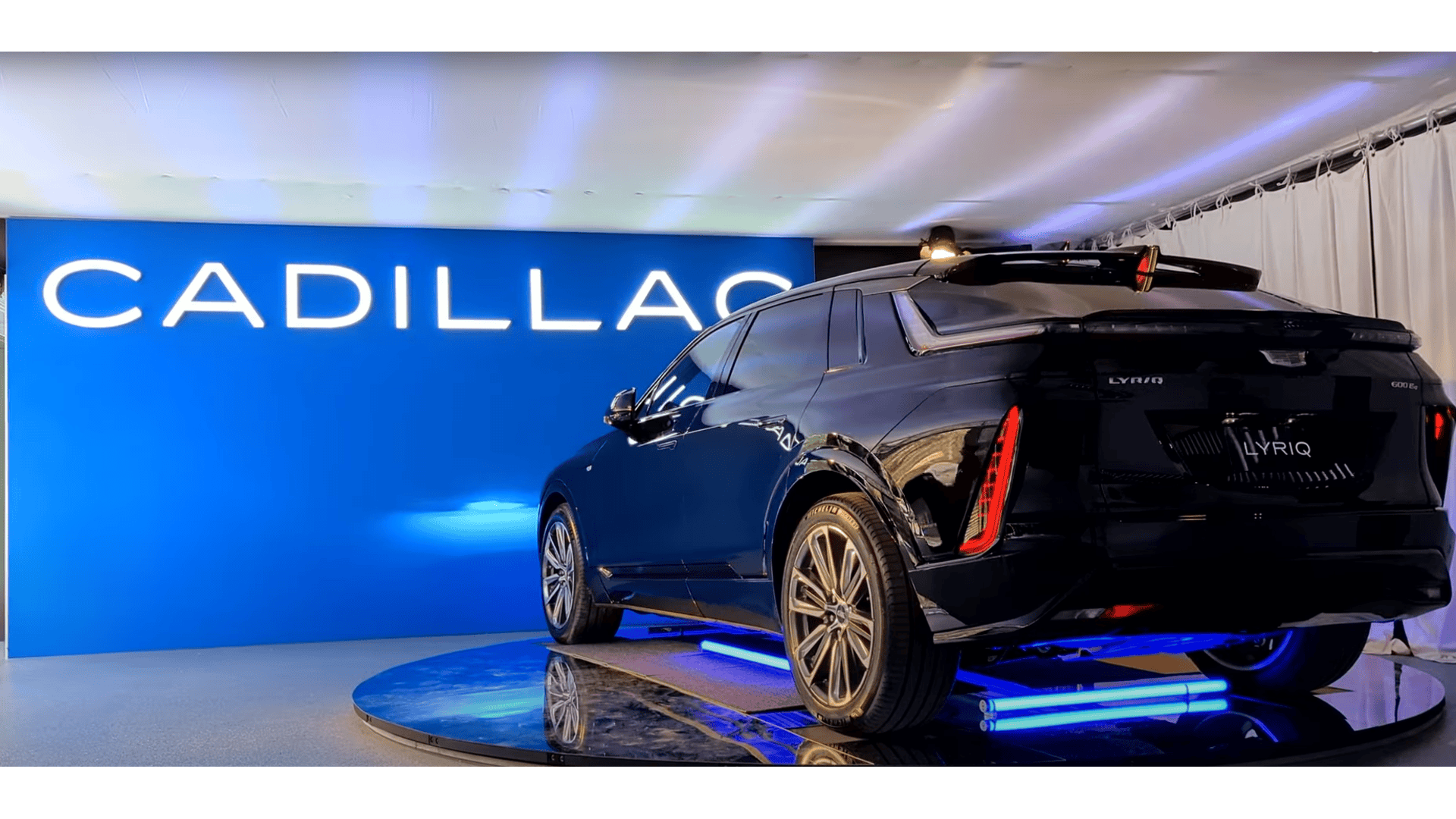 Cadillac Lyriq in front of a blue Cadillac Banner